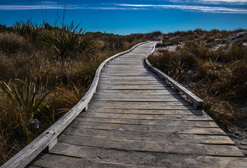 Wooden walkway on coastline with blue sky