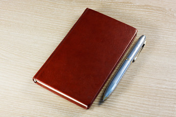 brown notebook with pen on office desktop