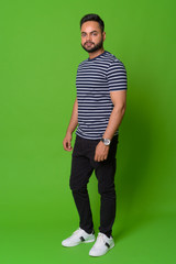 Young bearded Indian man against green background