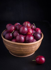 Fototapeta na wymiar ripe plums in the bowl on black background