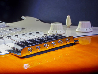 Electric guitar of dark color with light inserts with metal strings