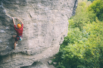 A man in helmet climbs the rock.