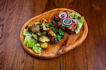 Board with barbecue and baked potatoes on a wooden table