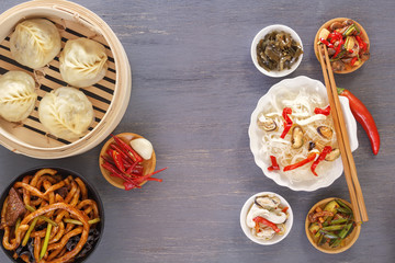 Dishes of Chinese cuisine in assortment. Steam dumplings, noodles, salads, vegetables, mushrooms, seafood. Top view. Copy space