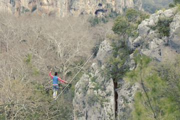 Highliner on a rope. Highline on a background of mountains. Extreme sport on the nature. Balancing on the sling. Equilibrium at altitude.