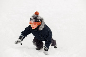 Fototapeta na wymiar childhood, leisure and season concept - happy little boy in winter clothes outdoors
