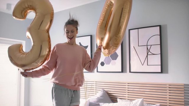 Woman with golden balloons celebrating her birthday in bed