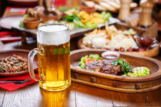 A glass of light beer on the background of a table with snacks.