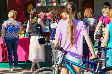 The girl is standing next to a bicycle in a big metropolis.