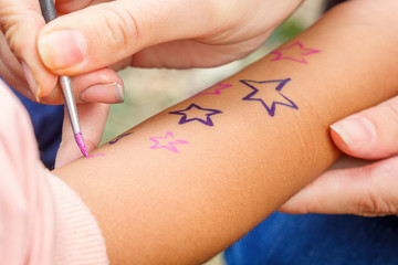 girl draws paint on the child's hand. Close-up