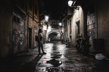 Naklejka na ściany i meble Anonymous woman on dark street at night