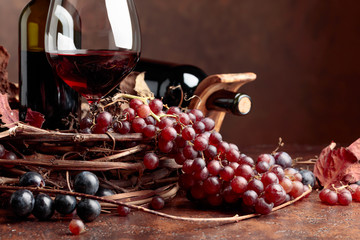 Red wine and fresh grapes with dried up vine leaves.