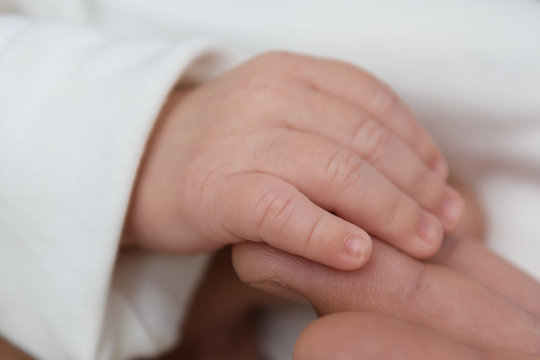 The hand of the newborn in his father's hand. The tenderness of motherhood is in the details. Procreation in childbirth and love. 