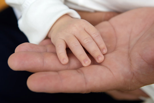 The hand of a newborn child in his father's hand. The tenderness of motherhood is in the details. Procreation in childbirth and love. 