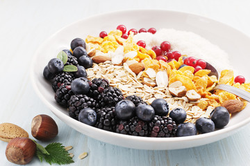 Healthy breakfast. Granola, muesli with coconut, corn flakes and fresh berries on light blue background. Top view. Copy space.