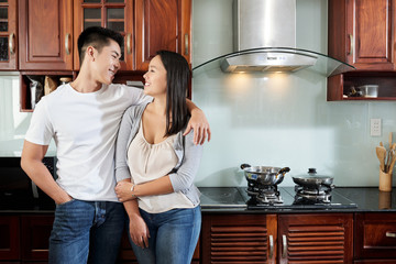 Young happy couple in love standing in kitchen and looking at each other