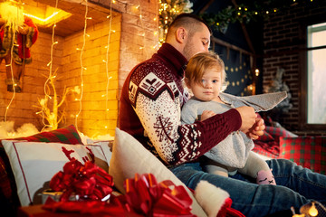 Father with a baby in a Santa Claus hat in a Christmas room on Christmas Day.