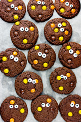 Halloween cookies, homemade chocolate cookies with candy eyes and chocolate orange and yellow candy, traditional halloween treats for kids
