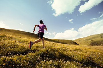 Young fitness woman trail runner running on grassland