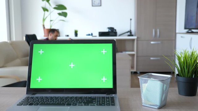 Laptop with green screen chroma on it in the middle of living room. The screen is with markers for traking. Dolly slider 4K footage
