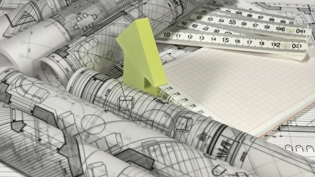 Blueprints - rolls of architectural drawings, notebook, yardstick - folding ruler and house symbol from a pack of yellow stickers smoothly rotate on the surface of the architectural drawings