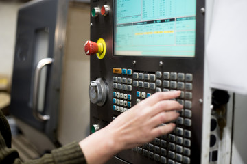 The hand enters data on the control panel of the lathe