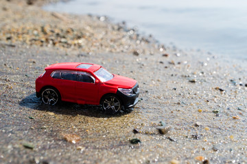 Fototapeta na wymiar one red toy car on the beach, the beach in the summer