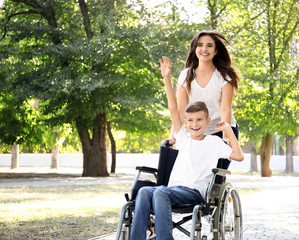 Teenage boy in wheelchair with his mother walking outdoors