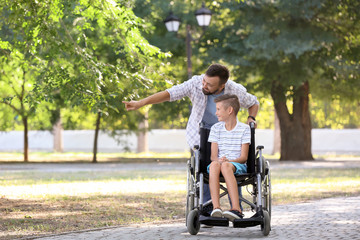 Teenage boy in wheelchair with his father outdoors