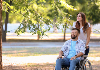 Young man in wheelchair with his wife walking outdoors