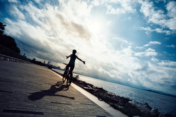 Hands free cycling woman riding Mountain Bike on sunrise seaside