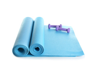 Yoga mats with dumbbells on white background
