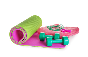 Yoga mat with dumbbells, jumping rope and towel on white background