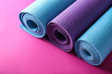 Different yoga mats on color background