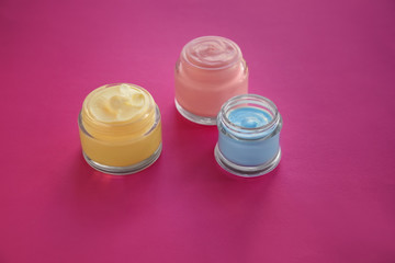 Jars with body cream on color table