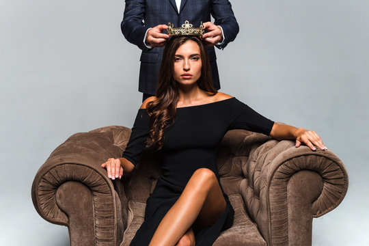 Queen in the city. Full length of young handsome men putting crown on his girlfriend while standing against white background