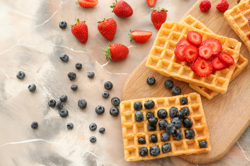 Delicious waffles with berries on table, top view