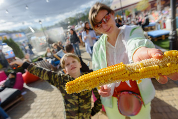 Portrait of happy mother and son holding grilled corn