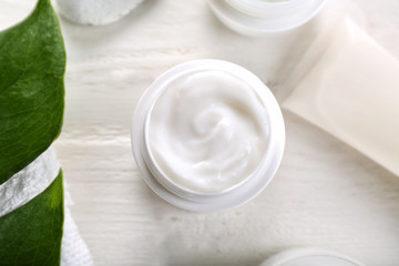 Jar with body cream on white table, top view