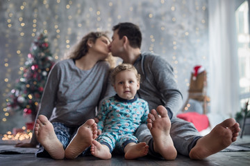 Fototapeta premium Happy pregnant family with little son at christmas decorated home near christmas tree