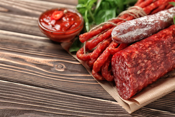 Different kinds of smoked sausages with sauce on wooden table