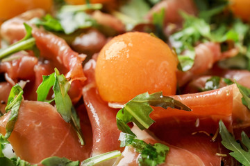 Delicious salad with melon balls and prosciutto, closeup