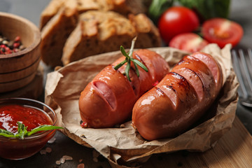 Tasty fried sausages with tomato sauce on table, closeup