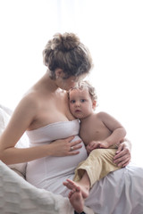 Light portrait of pregnant mother and son. Breastfeeding