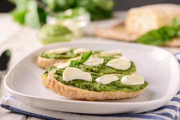 Bread with tasty basil sauce and mozzarella on plate