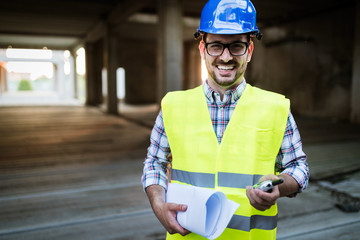 Architect holding rolled up blueprints at construction site