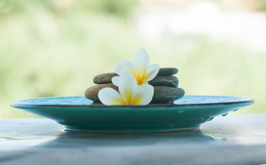 spa objects and stones for massage treatment in plate on marble background.