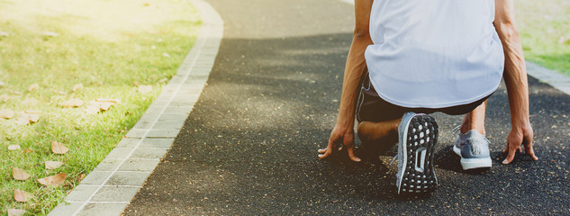 Athlete men in running start pose at walking way in public park. Healthy life and diet concept....