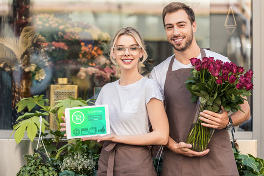 happy florists holding tablet with shopping appliance and burgundy roses near flower shop