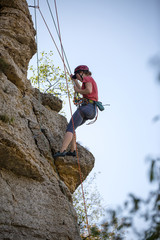 Fototapeta premium Photo of athlete woman in helmet clambering over rock